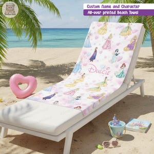 Puede incluir: Una toalla de playa blanca con un estampado integral de varias princesas de dibujos animados y corazones en tonos pastel. El centro de la toalla muestra el nombre Dulcie en una fuente cursiva. La toalla est&aacute; sobre una tumbona blanca.