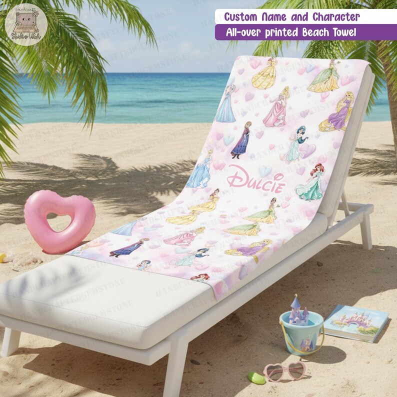 Puede incluir: Una toalla de playa blanca con un estampado integral de varias princesas de dibujos animados y corazones en tonos pastel. El centro de la toalla muestra el nombre Dulcie en una fuente cursiva. La toalla est&aacute; sobre una tumbona blanca.