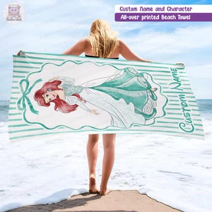 Puede incluir: Una toalla de playa rectangular con un patr&oacute;n de rayas blancas y verde azulado, una ilustraci&oacute;n central de un personaje pelirrojo con vestido verde azulado, enmarcada por un lazo y el texto Custom Name impreso verticalmente en verde.