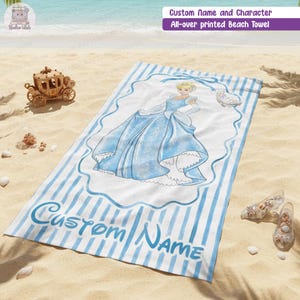 Puede incluir: Una toalla de playa rectangular con un patr&oacute;n de rayas verticales azules y blancas. El centro muestra un gr&aacute;fico de un personaje rubio con un vestido de gala azul dentro de un marco decorativo, con el texto Custom Name en letra azul.