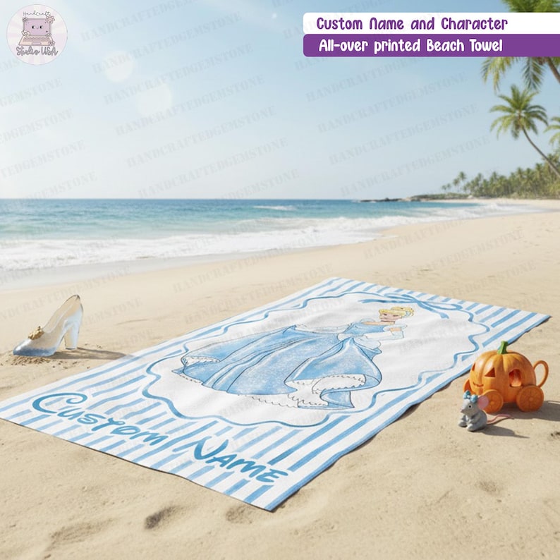 Puede incluir: Una toalla de playa rectangular con un patr&oacute;n de rayas azules y blancas y una ilustraci&oacute;n central de un personaje con vestido azul. El texto Custom Name est&aacute; impreso en azul. Un zapato de cristal y una carroza de calabaza est&aacute;n cerca.