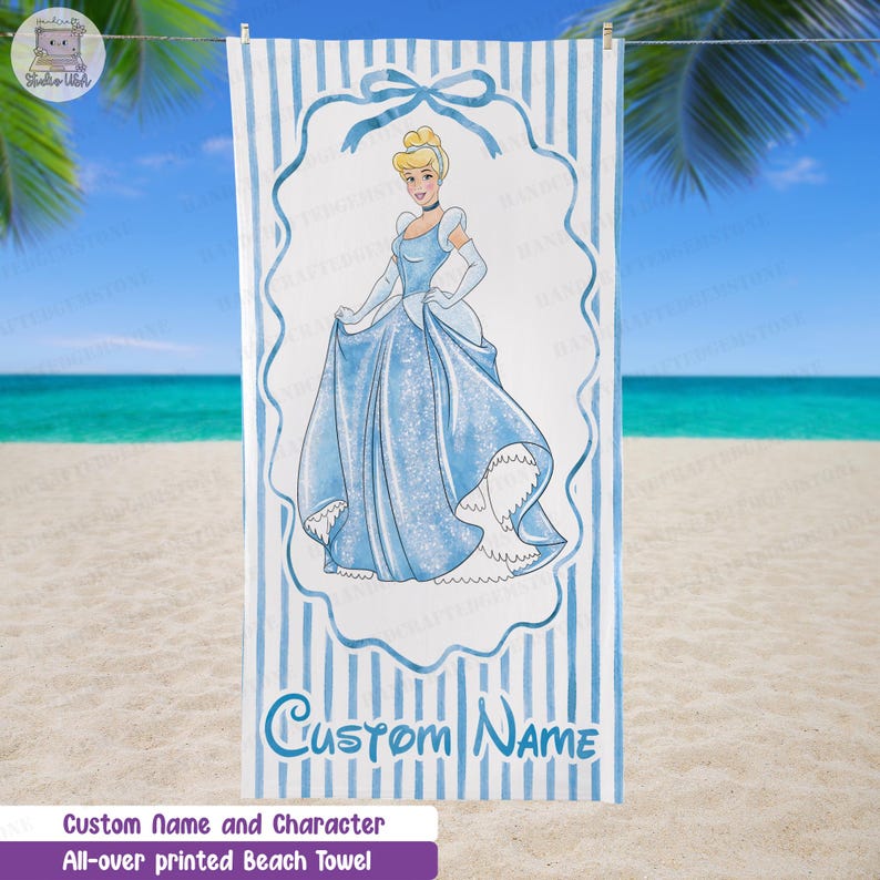 Puede incluir: Una toalla de playa rectangular con un patr&oacute;n de rayas verticales en azul claro y blanco. En el centro, un marco azul contiene una ilustraci&oacute;n de Cenicienta con un vestido de gala azul brillante. El texto CUSTOM NAME aparece en la parte inferior.