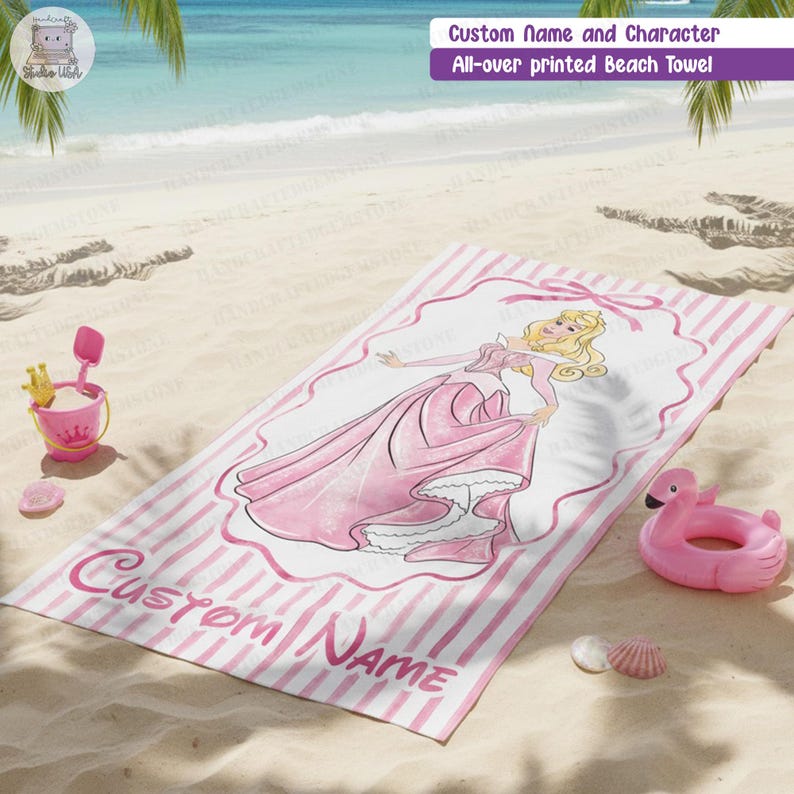 Puede incluir: Una toalla de playa rectangular con un patr&oacute;n de rayas rosas y blancas y una ilustraci&oacute;n central de un personaje rubio con un vestido rosa dentro de un marco decorativo. El texto Custom Name est&aacute; impreso en cursiva rosa en la parte inferior.