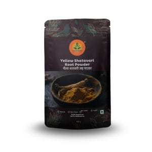 Op de afbeelding: Een donkerbruin zakje met gele Shatavari-wortelpoeder. Het zakje heeft de tekst "CUROHERS" en "Yellow Shatavari Root Powder" in het Engels en Hindi. Een kleine kom met geel poeder en een wortel zijn zichtbaar. Het zakje is gelabeld als natuurlijk, niet-toxisch, niet-GMO en veganistisch.
