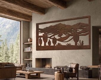 May include: A large, rectangular metal wall art piece depicting a desert landscape with cacti and mountains. The artwork is made of rusted metal and hangs above a fireplace in a living room with a rustic aesthetic. The room features wooden beams and a large window.