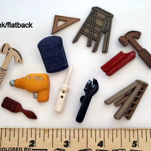 May include: A set of 10 colorful plastic buttons shaped like tools, including a hammer, a drill, a screwdriver, a wrench, a paintbrush, a ladder, a paint can, and a ruler. The buttons are all flat on the back and have a shank for sewing.