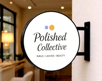 May include: A circular, black-framed wall-mounted sign with a white face. The sign features the text Polished Collective in a black script font, with the words NAILS | LASHES | BEAUTY below, and two small circles in blue and yellow above.