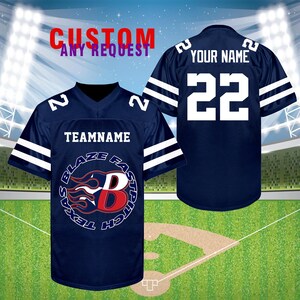 K&ouml;nnte beinhalten: Marineblaues Baseball-Trikot mit wei&szlig;en Streifen auf den &Auml;rmeln und Schultern. Auf der Vorderseite steht der Text "TEAMNAME" &uuml;ber einem Logo mit den Worten "TEXAS BLAZE FASTPITCH" und einem stilisierten "B". Auf der R&uuml;ckseite stehen "YOUR NAME" und die Nummer "22".