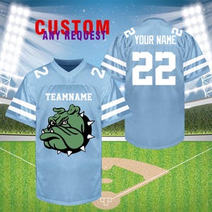 K&ouml;nnte beinhalten: Hellblaues Football-Trikot mit wei&szlig;en Streifen auf den &Auml;rmeln und Schultern. Das Trikot hat die Nummer 22 und den Text "YOUR NAME" auf dem R&uuml;cken. Die Vorderseite zeigt eine gr&uuml;ne Bulldoggen-Grafik und den Text "TEAMNAME". Der Text "CUSTOM ANY REQUEST" steht oben.