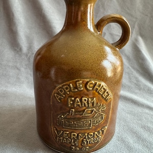 May include: A set of three ceramic mugs with a speckled, matte finish. The mugs are in shades of cream, light gray, and dark gray. Each mug has a simple, minimalist design and a rounded handle.