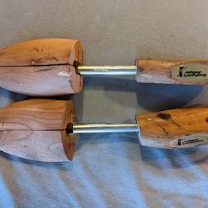 May include: Two wooden shoe trees with metal rods and leather pull tabs. The shoe trees are made of light brown wood and have the words "Gentlemen's Jodhpur" printed on them. The shoe trees are designed to maintain the shape of shoes.