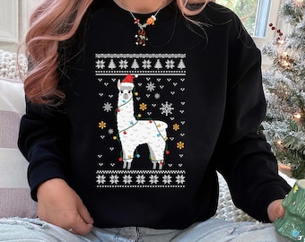 Könnte beinhalten: Schwarzes Sweatshirt mit einem weißen Lama, das einen Weihnachtsmannhut und Lichterketten trägt. Das Design umfasst Schneeflocken, Weihnachtsbäume und einen dekorativen Rand. Ein festlicher Weihnachts-Pullover.