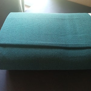 May include: A teal blue fabric book cover with a subtle texture.