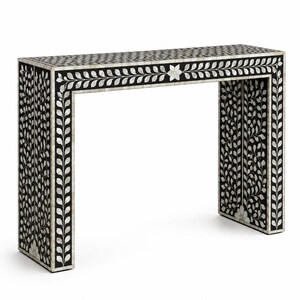 May include: A black and white console table with a floral and leaf design. The table features a rectangular top and two legs, with intricate inlaid patterns. The design includes a border of leaf-like shapes and floral accents.