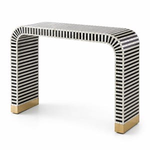 May include: A modern console table with a distinctive design. The table features a black and white striped pattern across its curved top and legs. The base of the legs has a gold finish. The table measures approximately 48 inches long.