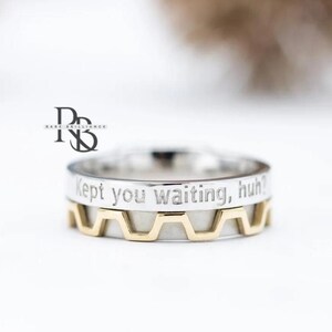 May include: A two-tone ring with a silver band and a gold-colored zigzag design. The silver band has the engraved text "Kept you waiting, huh?" The ring is a piece of jewelry.