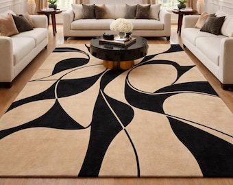 May include: A beige and black abstract patterned area rug in a living room setting. The rug features a bold, geometric design with black shapes against a neutral background. The room includes white sofas, a black coffee table, and a chandelier.