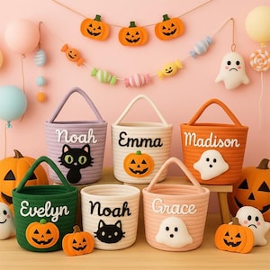 May include: A collection of Halloween-themed rope baskets in various colors, each with a name, a pumpkin or ghost applique, and a handle. The baskets are decorated with felt pumpkins, ghosts, and a candy garland, perfect for trick-or-treating.