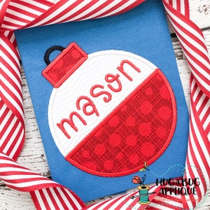 Puede incluir: Un flotador rojo y blanco con fondo blanco y el nombre "mason" escrito en cursiva negra. El flotador está en una camiseta azul.