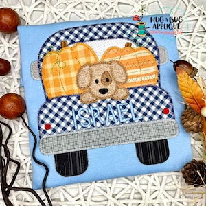 Puede incluir: Un camión azul y blanco a cuadros con un perro marrón asomándose por la parte de atrás. El camión lleva tres calabazas naranjas y el nombre "ISRAEL" está bordado en la parte de atrás.