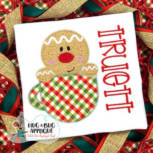 May include: A gingerbread person holding a red and green checkered mug with the name "Truett" embroidered in red on a white background.