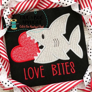 May include: A white shark with a gray pattern biting into a red heart with the text "LOVE BITES" below. The image is on a black background.