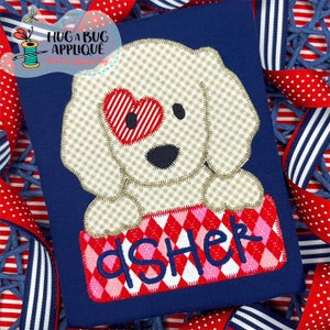 May include: A white dog with a red heart for an eye is peeking out of a red and pink box with the name "dShek" embroidered on it. The dog is on a blue background.