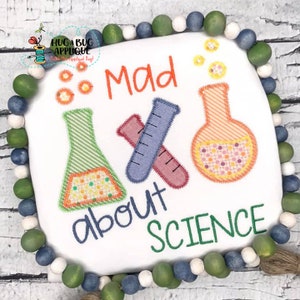 Puede incluir: Cuadrado blanco con las palabras "Mad about Science" e imágenes de equipos de laboratorio. El diseño incluye un vaso de precipitados verde, dos tubos de ensayo cruzados y un matraz naranja. El borde está hecho de cuentas de madera verdes, azules y blancas.