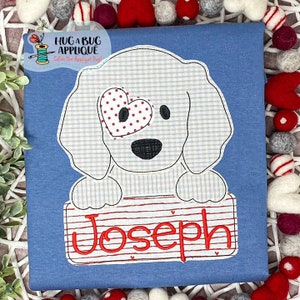 May include: A white dog with a red heart patch over one eye is holding a red and white striped sign with the name "Joseph" written in red. The dog is on a blue background.