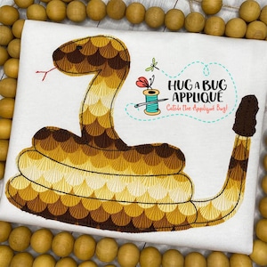 May include: Embroidered iron-on applique of a brown and yellow snake with the text "Hug a Bug Applique Catch the Applique Bug!"