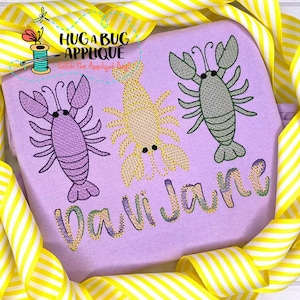 May include: Purple, yellow, and green embroidered crawfish designs on a light purple fabric with the name "Davi Jake" embroidered in a multi-colored font.