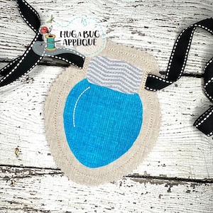 May include: A handmade applique featuring a blue liquid-filled bulb design with a gray and white striped top. The applique is surrounded by a beige fabric with a decorative stitch and is attached to a black ribbon with white stitching. The text "Huga Bug Applique" is visible.
