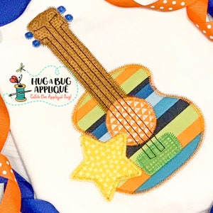 May include: A colorful guitar applique with a yellow star. The guitar is made of felt and has a striped design. The text "Hug a Bug Applique Catch the Applique Bug!" is visible in the image.
