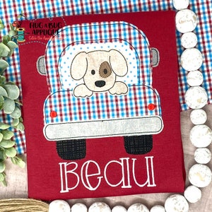 May include: Red and white gingham truck with a brown dog peeking out of the window. The truck has black wheels and a white bumper. The name "Beau" is embroidered below the truck.