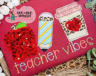 May include: Red, yellow, and blue teacher vibes embroidery design with a red apple, pencil, and coffee cup. The design is on a maroon fabric.