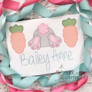 May include: Embroidered design featuring a gray bunny with pink feet and a pink flower tail, two orange carrots with green tops, and the name "Bailey Anne" in cursive.