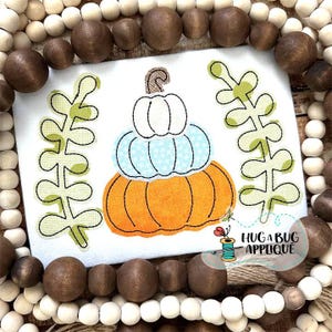 May include: A white, blue, and orange pumpkin applique with green leaves on a white background. The text "Hug A Bug Applique" is in the bottom right corner.