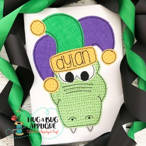 May include: Green and purple alligator applique with a jester hat and a yellow band that says "dylan".