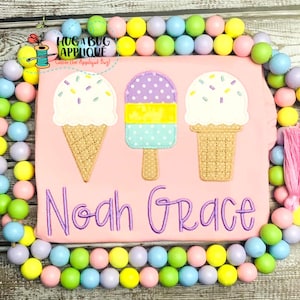 以下が含まれることがあります： アイスクリームコーンとアイスキャンディーが刺繍されたピンクのTシャツ。アイスクリームの下に「Noah Grace」という名前が紫で刺繍されています。
