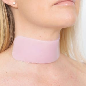 May include: A light pink neck support collar. The collar is made of a flexible material and is worn around the neck. The collar is designed to provide support and comfort.