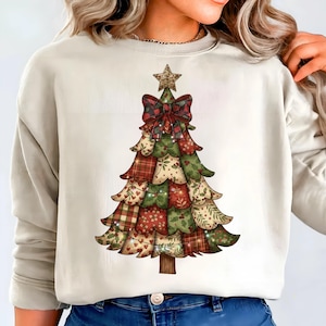 Könnte beinhalten: Cremefarbenes Sweatshirt mit einem Weihnachtsbaum-Design. Der Baum besteht aus Patchwork-Mustern in Rot, Grün und Beige, mit einem Stern und einer roten Karoschleife. Das Design hat eine rustikale, festliche Ästhetik für die Feiertage.