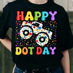 May include: Black t-shirt with a colorful graphic featuring the words "HAPPY DOT DAY" in rainbow colors. A dotted monster truck is in the center, surrounded by colorful dots.