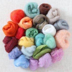 May include: A collection of 20 different colors of wool roving, arranged in a circle. The wool is soft and fluffy, and the colors are vibrant and varied.