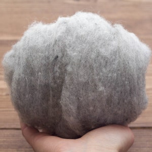 May include: A close-up of a clump of gray wool fibers. The wool is soft and fluffy, and it is perfect for felting or spinning.