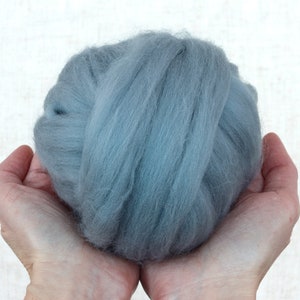 May include: A ball of light blue wool fibre held in two hands.