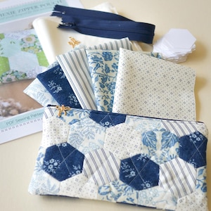 May include: A handmade Hexie zipper pouch with a blue and white floral pattern, surrounded by fabric swatches, a navy blue zipper, and a PDF sewing pattern. The pouch is quilted with a hexagon design.