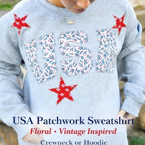 Op de afbeelding: Een grijze crewneck-trui met het woord "USA" in bloemenpatchworkletters en rode steraccenten. De tekst "USA Patchwork Sweatshirt Floral Vintage Inspired Crewneck or Hoodie" staat eronder.