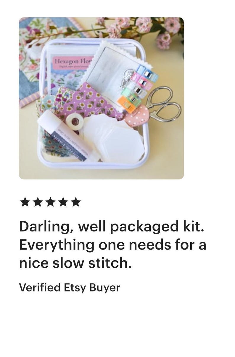 May include: A white rectangular box filled with sewing supplies, including fabric scraps, scissors, clips, and a glue stick. The box contains a booklet titled "Hexagon Flower". The kit is designed for slow stitch projects.