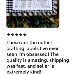 Op de afbeelding: Een wit label met de tekst "handmade with love" en de naam van de maker, Sarah Smith. Het label bevindt zich op een zwart-wit geruite stof. Het label is omrand door een decoratief frame.