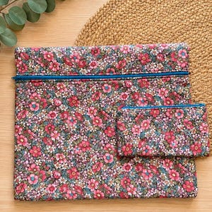 Pode incluir: Um conjunto de bolsas de tecido com padr&atilde;o floral, composto por uma bolsa grande com z&iacute;per e outra menor. O tecido apresenta um padr&atilde;o de flores rosa e vermelhas com detalhes verdes e azuis. Os z&iacute;peres s&atilde;o de um azul brilhante.